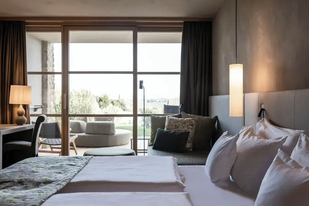 Zimmer mit Doppelbett und Zugang zu einer Terrasse mit Grünflächen