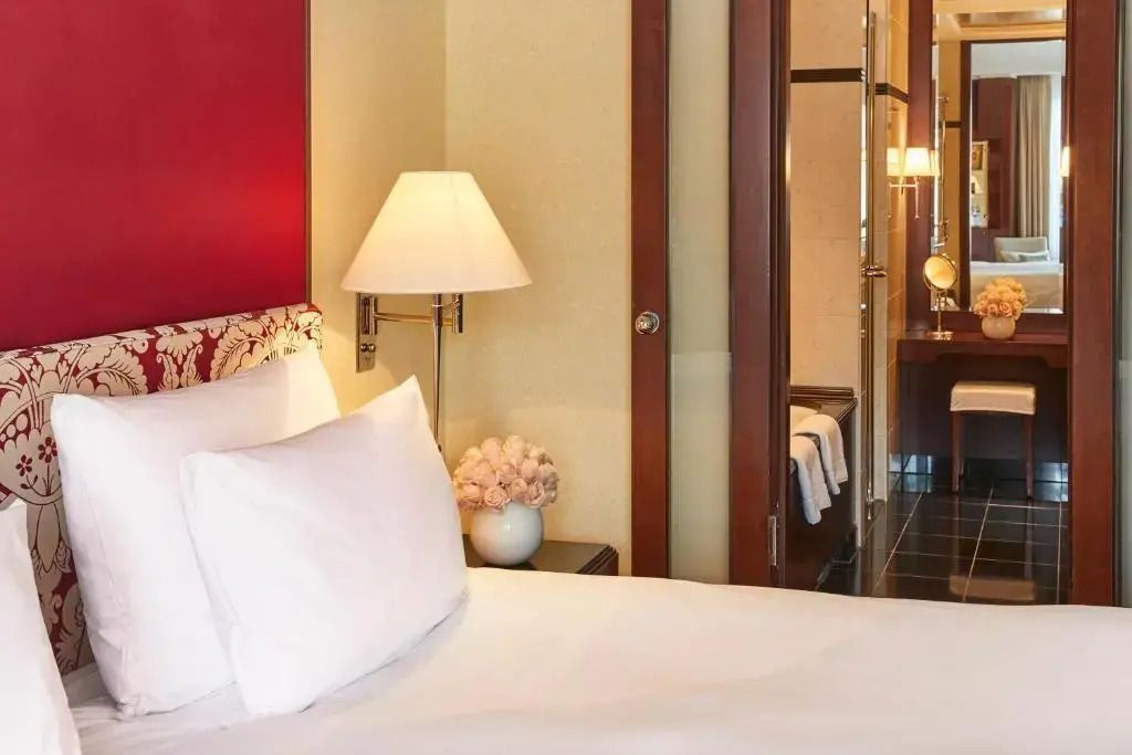 Teilansicht des stilvoll dekorierten Doppelzimmers mit Blumen und Leselampe im Adlon Kempinski