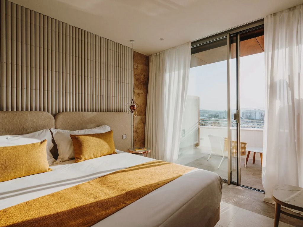Sonnenlicht durchflutetes Zimmer mit Zugang zu einem Balkon und Aussicht auf die Bucht