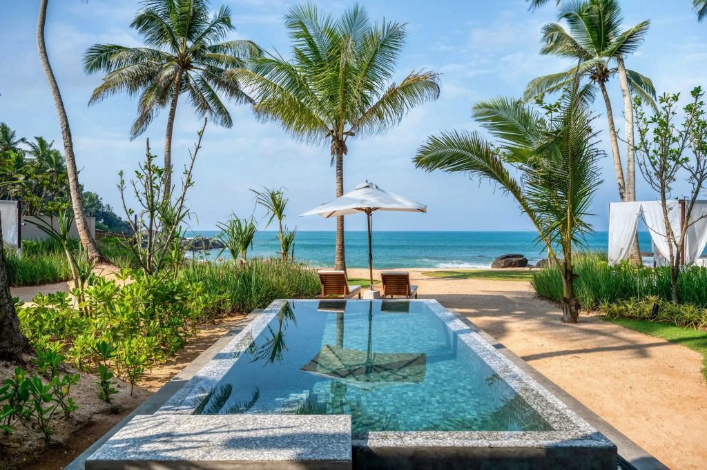 Infinity Pool mit Meerblick umgeben von Palmen am Strand