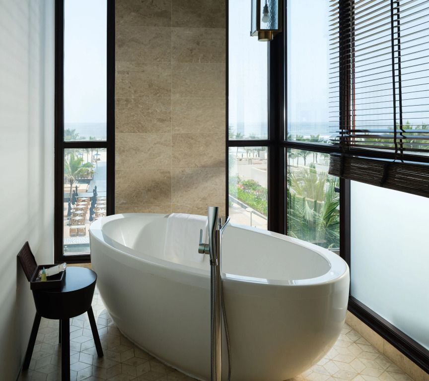 Elegantes Badezimmer mit freistehender Badewanne und großen Fenstern