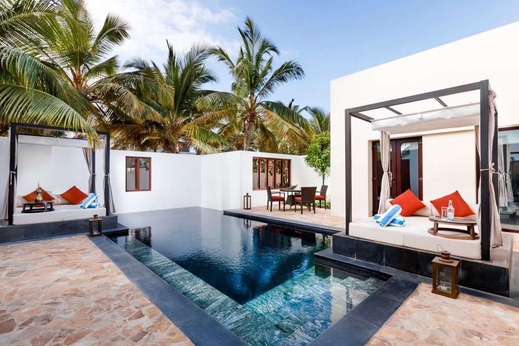 Pool mit Liegestühlen umgeben von Palmen in der Villa