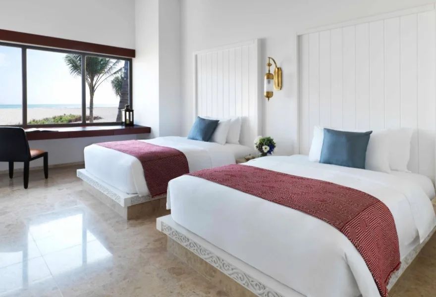 Schlafzimmer mit zwei Einzelbetten und Blick auf das Meer durch ein großes Fenster