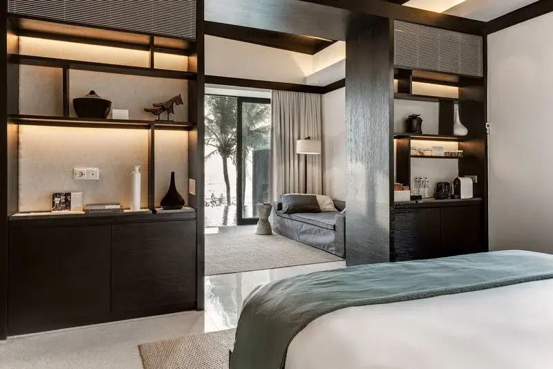 Luxuriöses Zimmer mit Doppelbett und Ausblick auf Palmen durch eine große Glastür