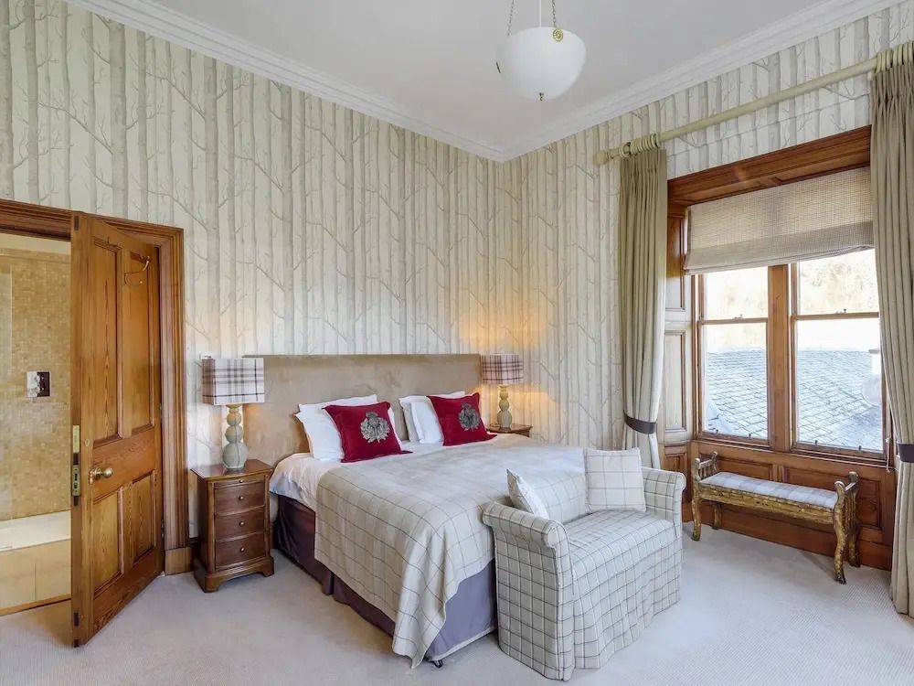 Luxuriöses Schlafzimmer mit stilvollen Tapeten und einem großen Fenster mit Bergblick