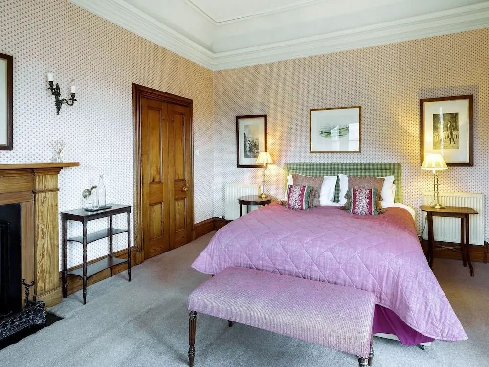 Gemütliches Schlafzimmer mit violetter Tagesdecke und eleganten Holzmöbeln