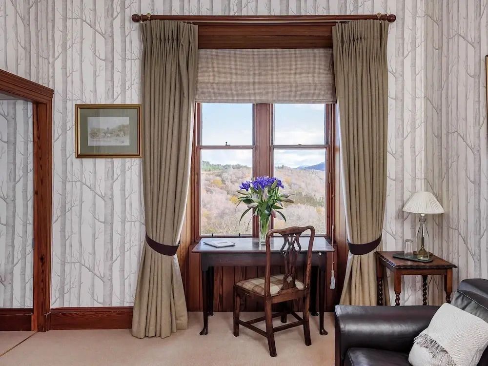 Schreibtisch vor einem Fenster mit Bergblick und eleganten Vorhängen