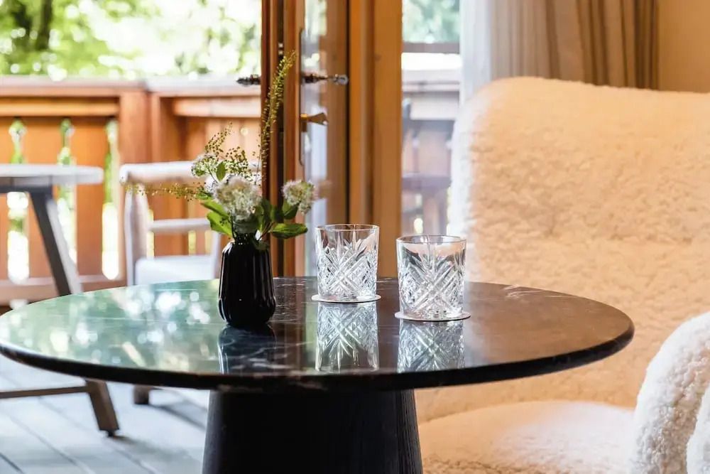 Elegantes Zimmer mit Marmortisch, Blumen und zwei Kristallgläsern vor Balkon