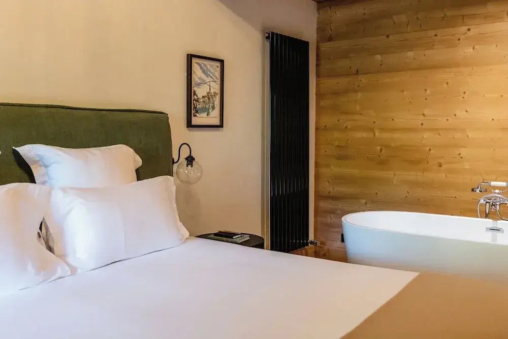 Einladendes Bett in modernem Zimmer mit freistehender Badewanne