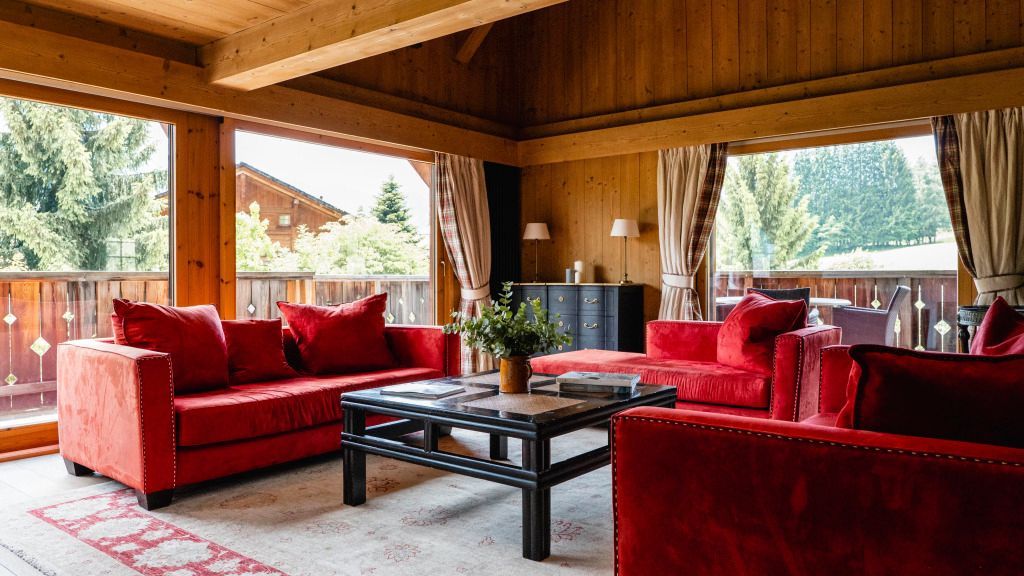 Gemütliches Wohnzimmer mit Holzwänden und roten Sofas in Chalet-Atmosphäre