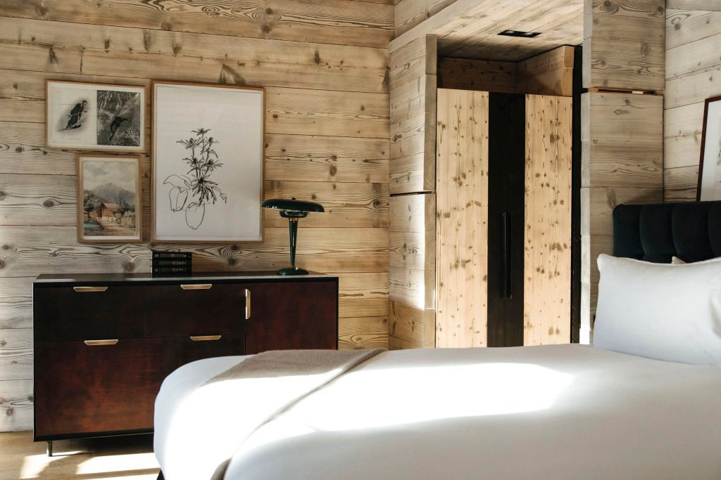 Deluxe Zimmer mit Holzwänden, weißem Bett, Kunst und stilvoller Beleuchtung.
