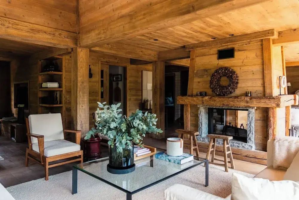 Gemütlicher Wohnbereich mit Kamin und rustikalen Holzwänden im Chalet-Stil.