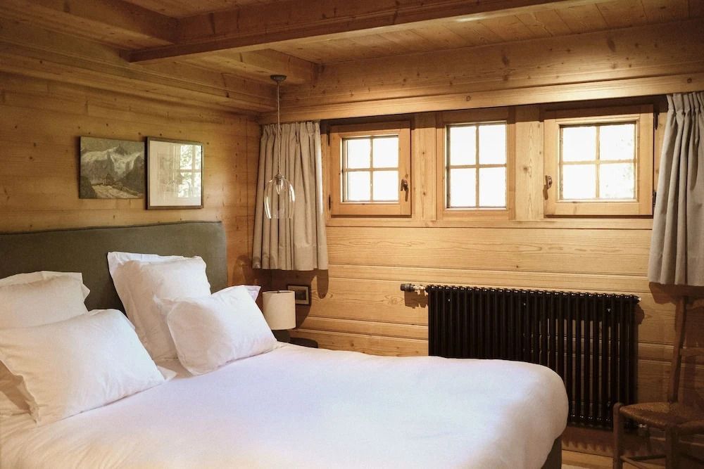 Gemütliches Schlafzimmer in Holzvertäfelung mit Doppelbett und Fenstern