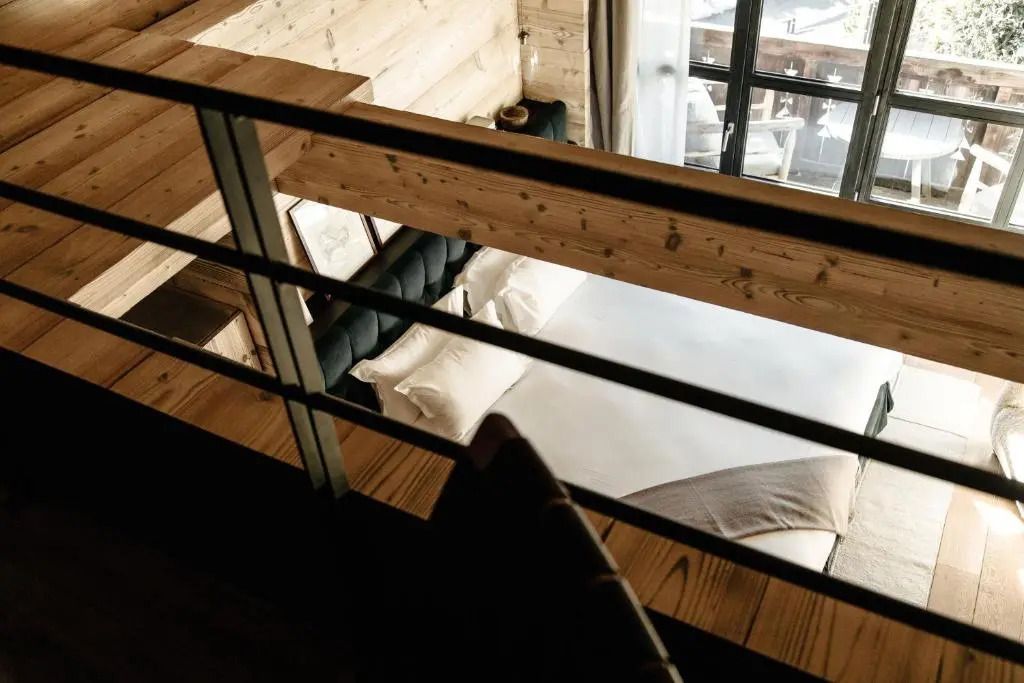 Blick auf ein gemütliches Bett und Holzwände im Dachboden eines Hotelzimmers