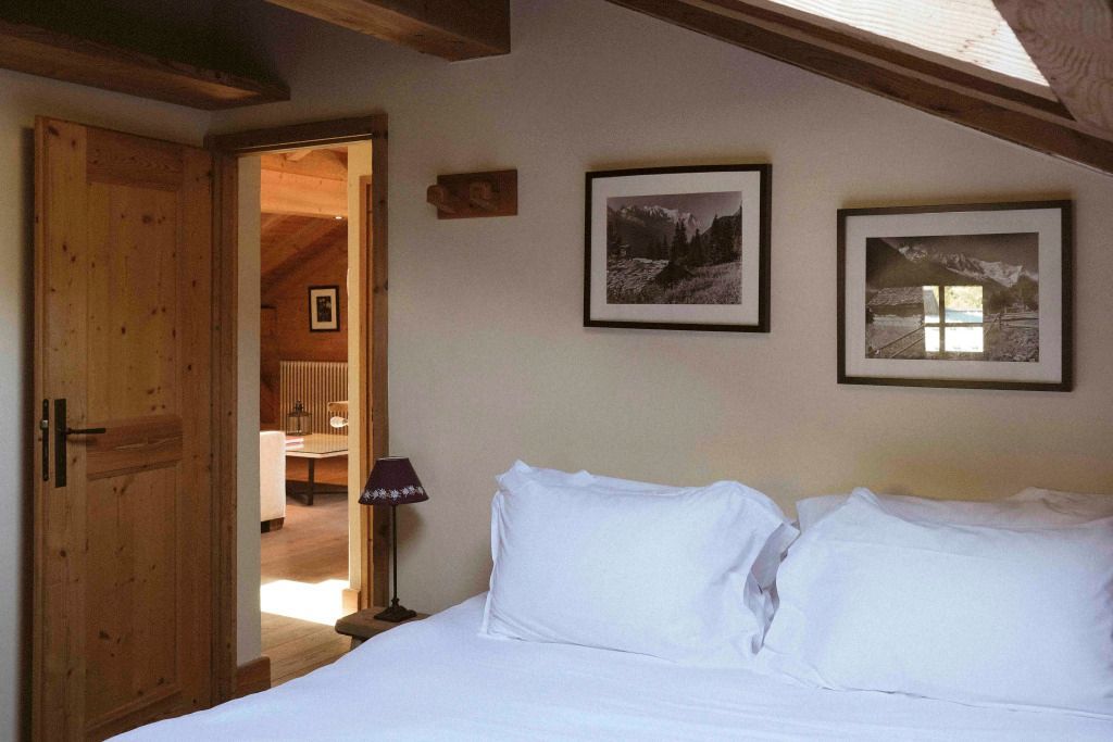 Gemütliches Schlafzimmer mit Holzbalkendecke und Kunstwerken an der Wand