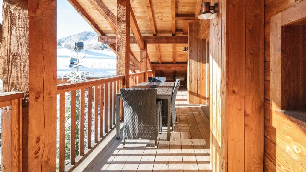 Holzveranda mit Sitzgelegenheit und Blick auf verschneite Landschaft