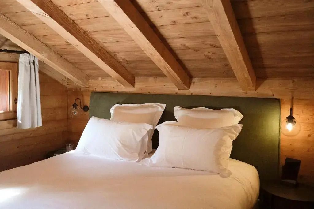 Dachzimmer mit Holzbalken und gemütlichem Doppelbett