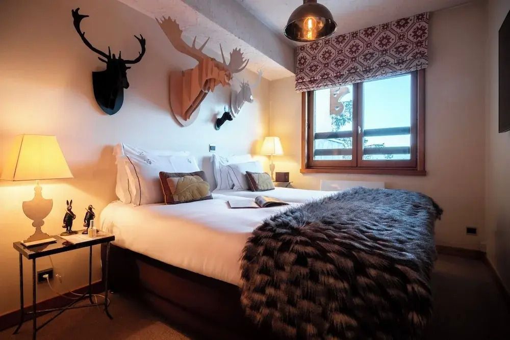 Gemütliches Schlafzimmer mit Hirschdekoration und flauschiger Decke. Warme Beleuchtung.