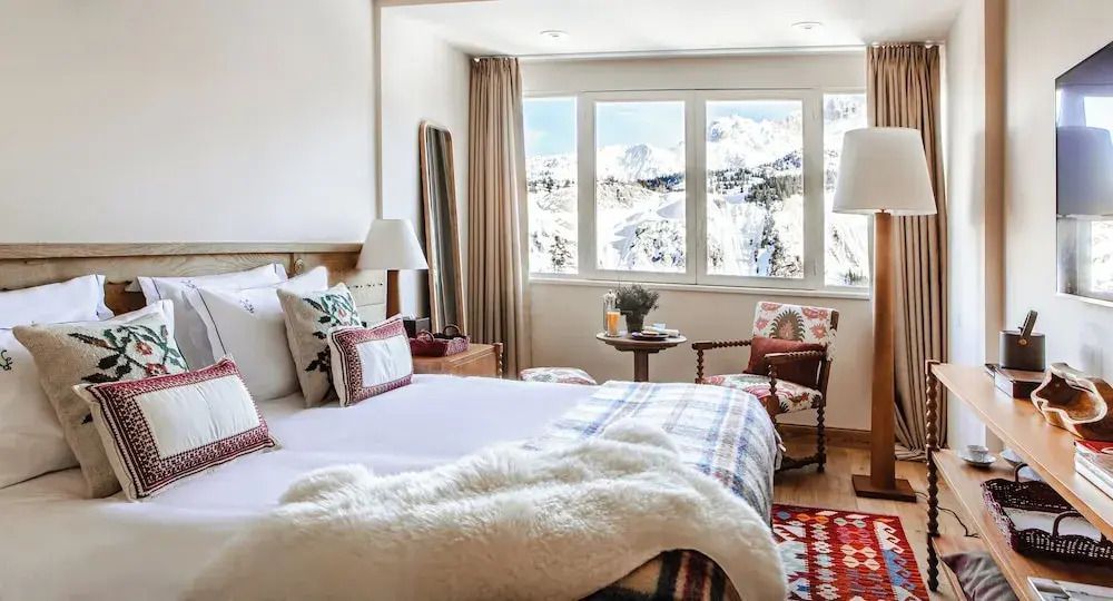 Helles Zimmer mit gemütlichem Doppelbett und Blick auf schneebedeckte Berge