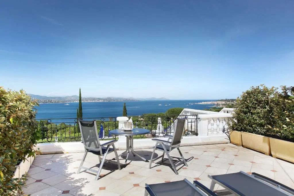 Sonnige Terrasse mit Tisch und Stühlen sowie herrlicher Aussicht auf das Meer