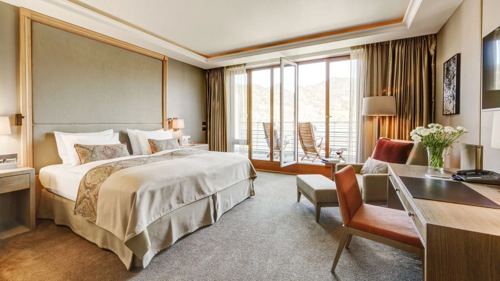 Luxuriöses Deluxe Zimmer mit Kingsize-Bett und Seeblick von privater Terrasse.