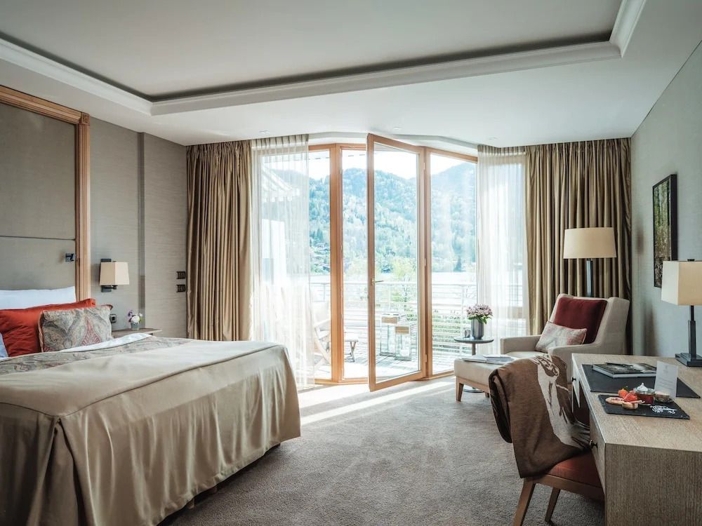 Helles Deluxe Zimmer mit Balkon und atemberaubendem Blick auf den See und Berglandschaft.