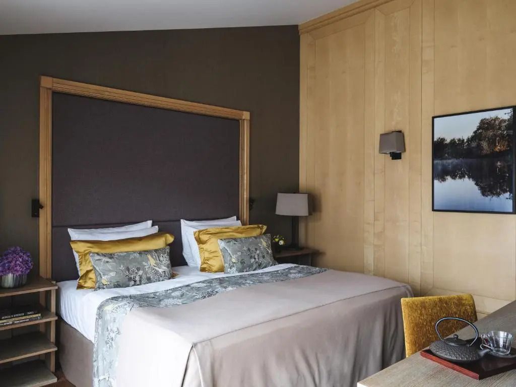 Helles Doppelbett in der Junior-Suite mit stilvollen Kissen und Holzelementen.