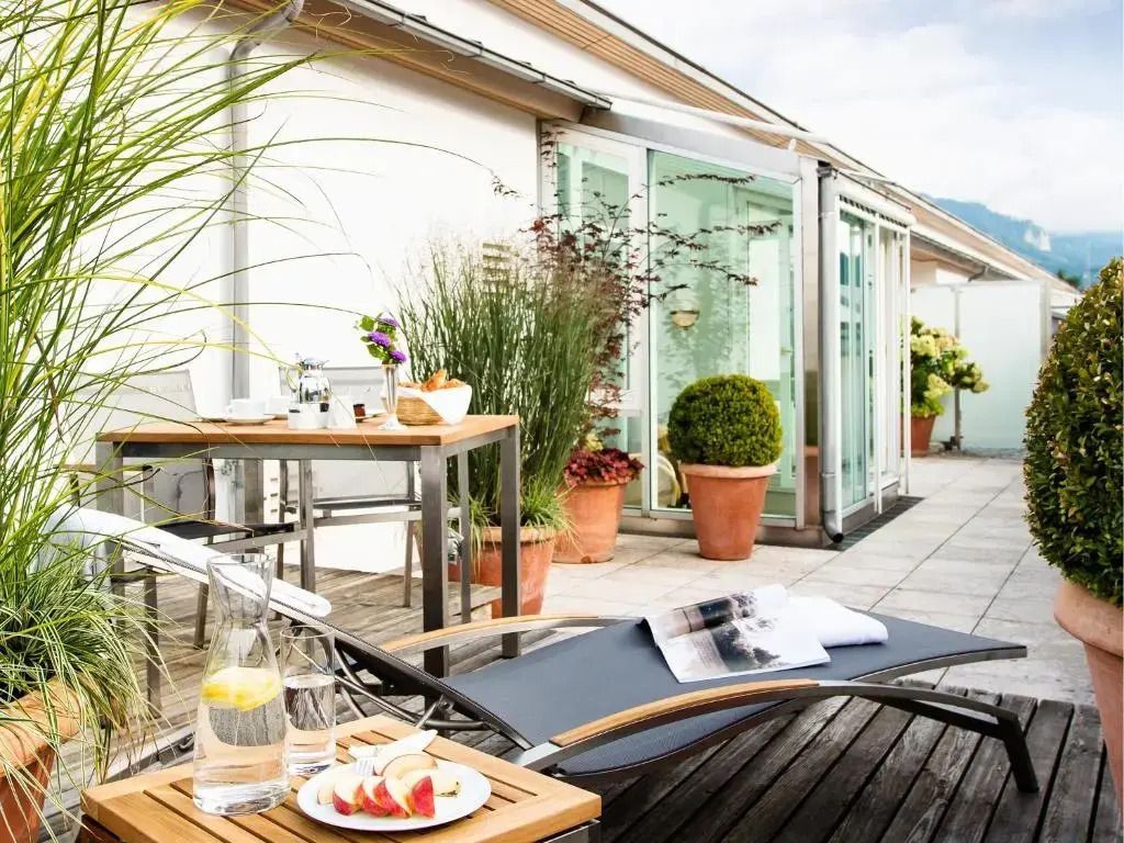 Dachterrasse mit Liegestuhl, Tisch und Pflanzen für entspannte Stunden im Freien.