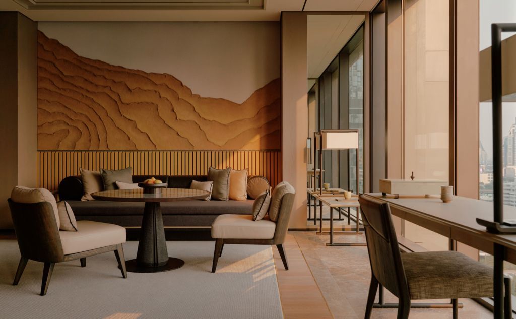 Lounge-Bereich im Hotel mit Sofas und künstlerischer Wanddekoration.