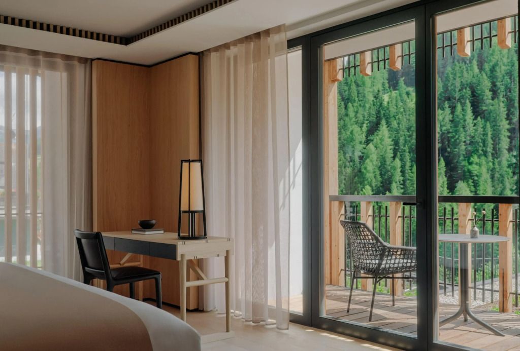 Helles Zimmer mit Balkon, Blick auf den Wald und einem eleganten Schreibtisch