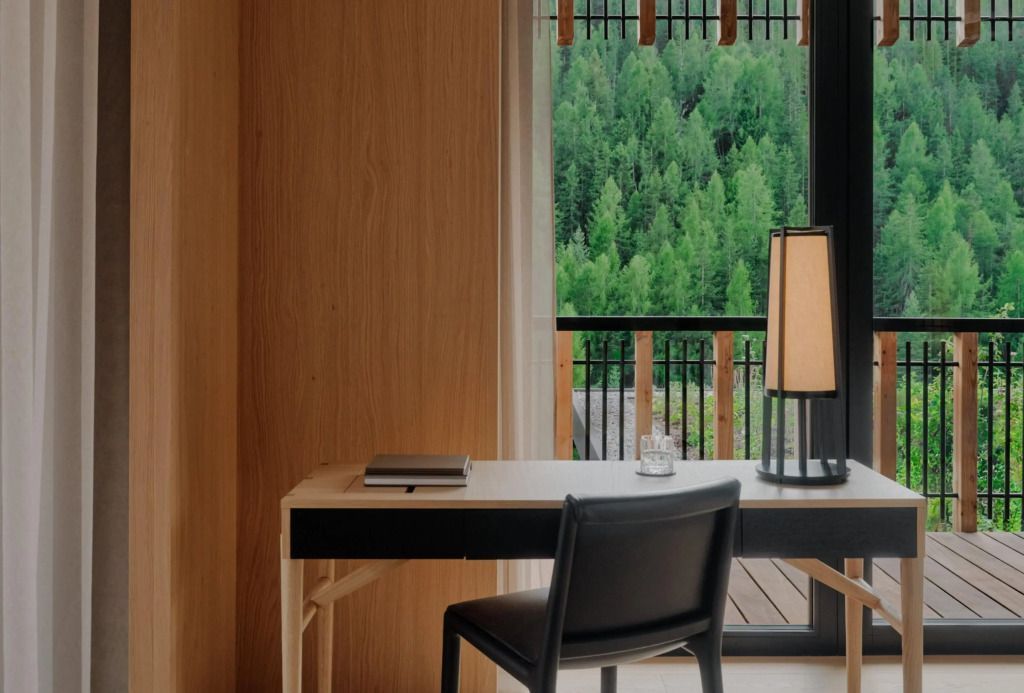 Schreibtisch in einem Hotelzimmer mit Blick auf grüne Wälder