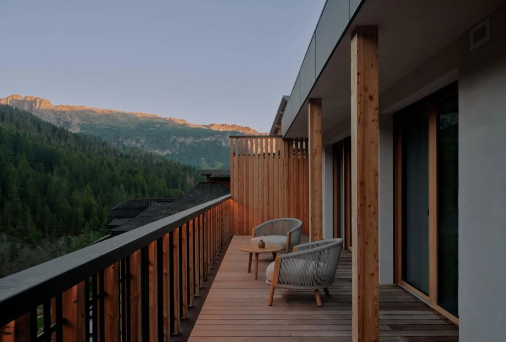 Holzbalkon mit gemütlichen Sesseln und Bergblick im Abendlicht
