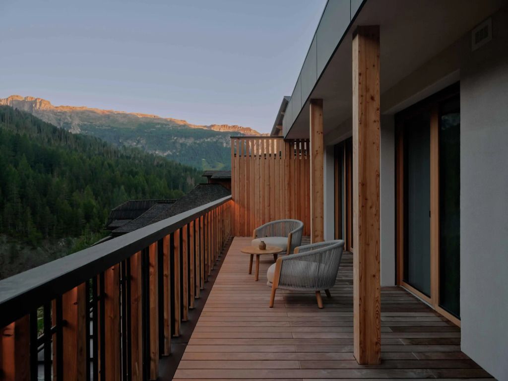 Holzterrasse mit Sitzgelegenheiten und Blick auf Berge im Aman Rosa Alpina
