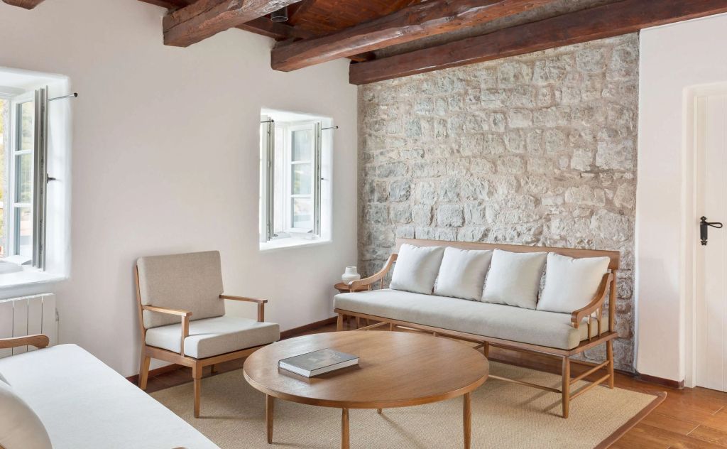 Sitzecke mit Sofa und Sessel vor einer Steinwand