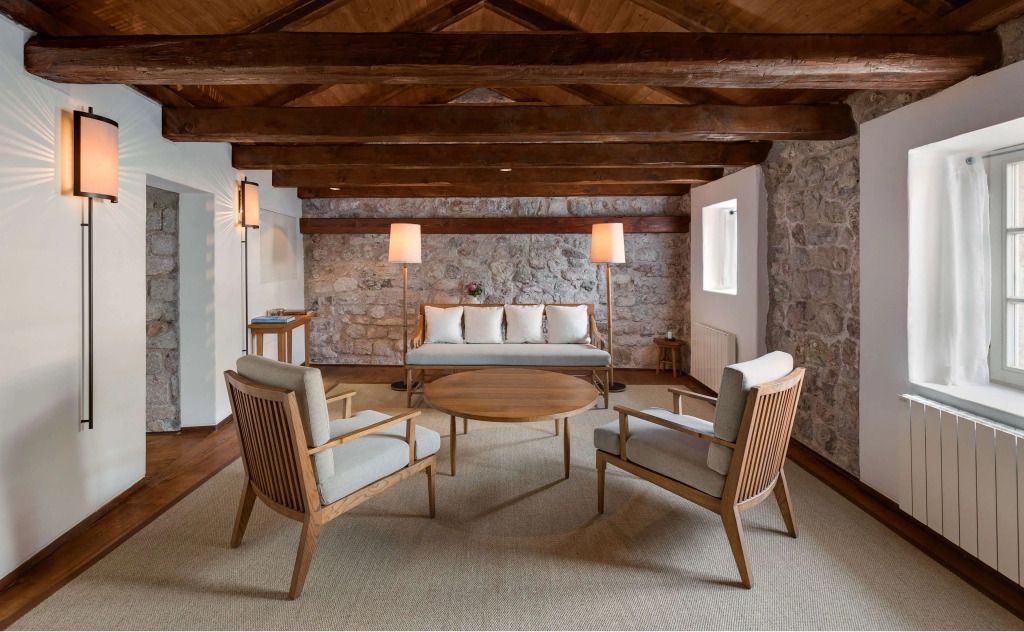 Stilvoll eingerichteter Wohnbereich mit Holzmöbeln und Steinwand im Hotelzimmer