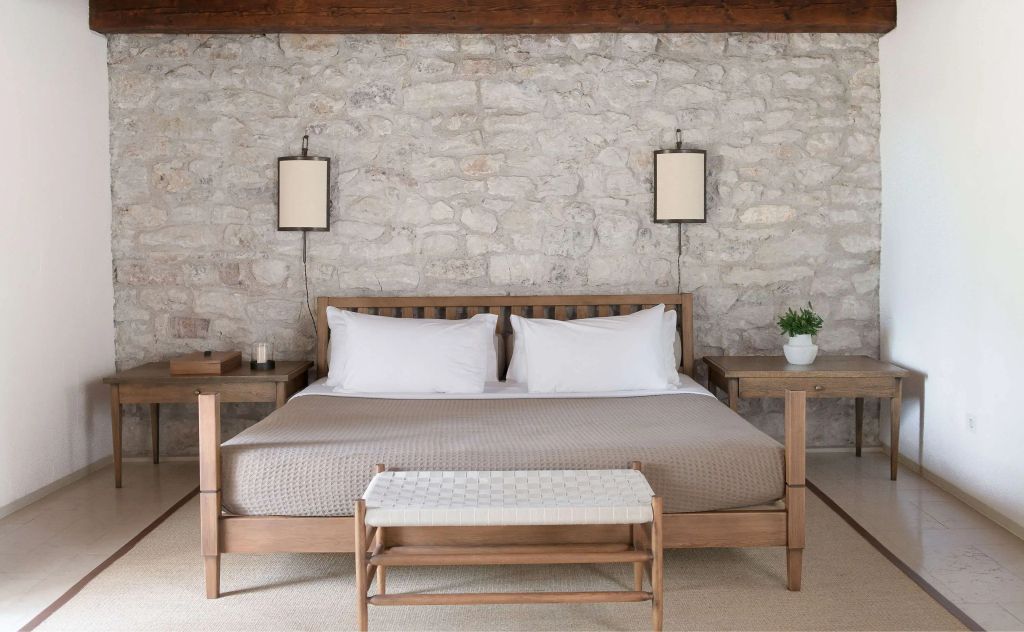 Gemütliches Schlafzimmer mit Steinwand und großem Holzbett im Hotel Aman Sveti Stefan