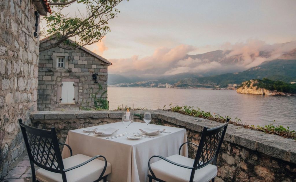 Terrasse mit Essbereich und Blick aufs Meer bei Sonnenuntergang im Hotel Aman Sveti Stefan