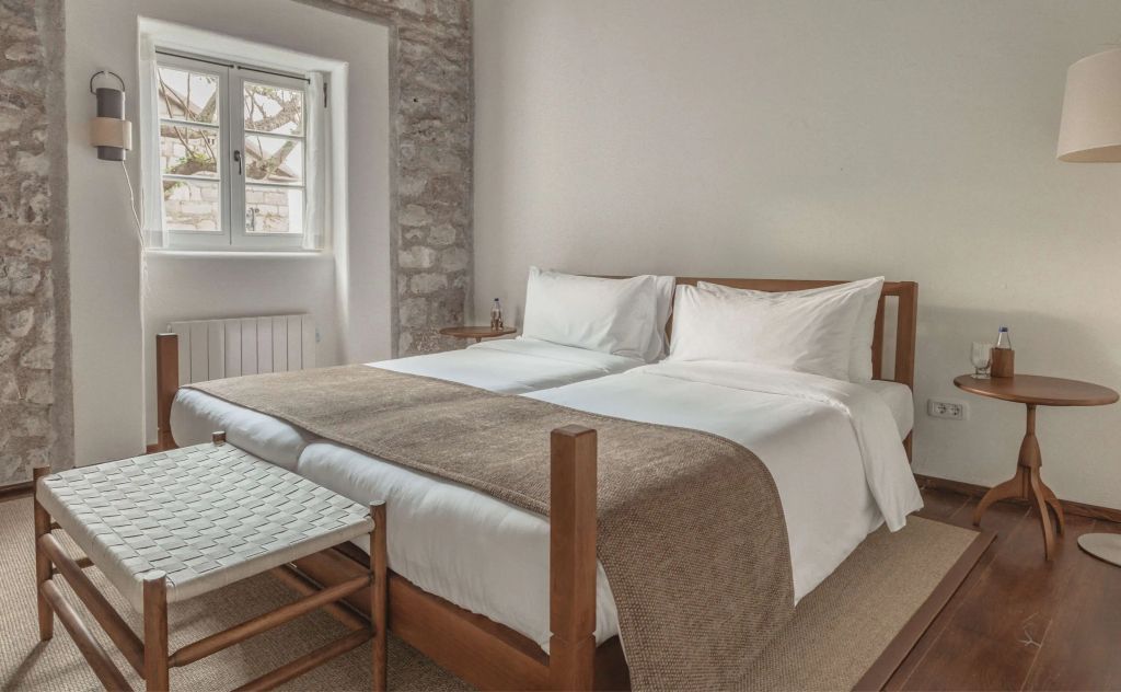 Helles Schlafzimmer mit zwei Betten und Steinakzenten im Hotel Aman Sveti Stefan
