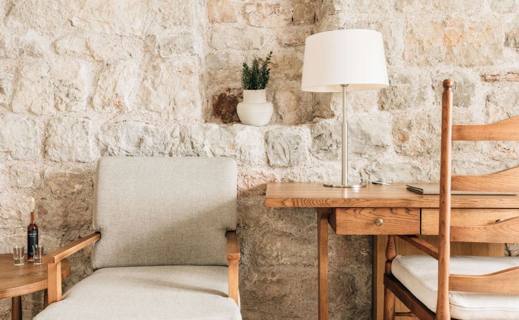 Sitzecke mit Steinwand und kleinem Tisch im Standardzimmer des Aman Sveti Stefan