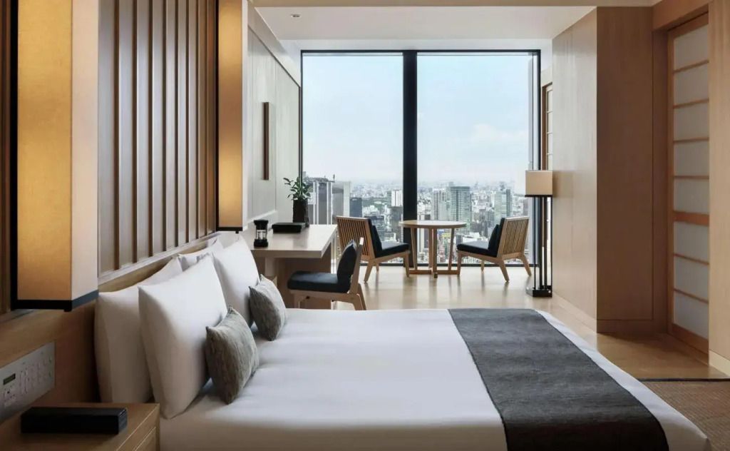 Stilvolles Hotelzimmer mit Doppelbett und Panoramafenster mit Stadtblick.