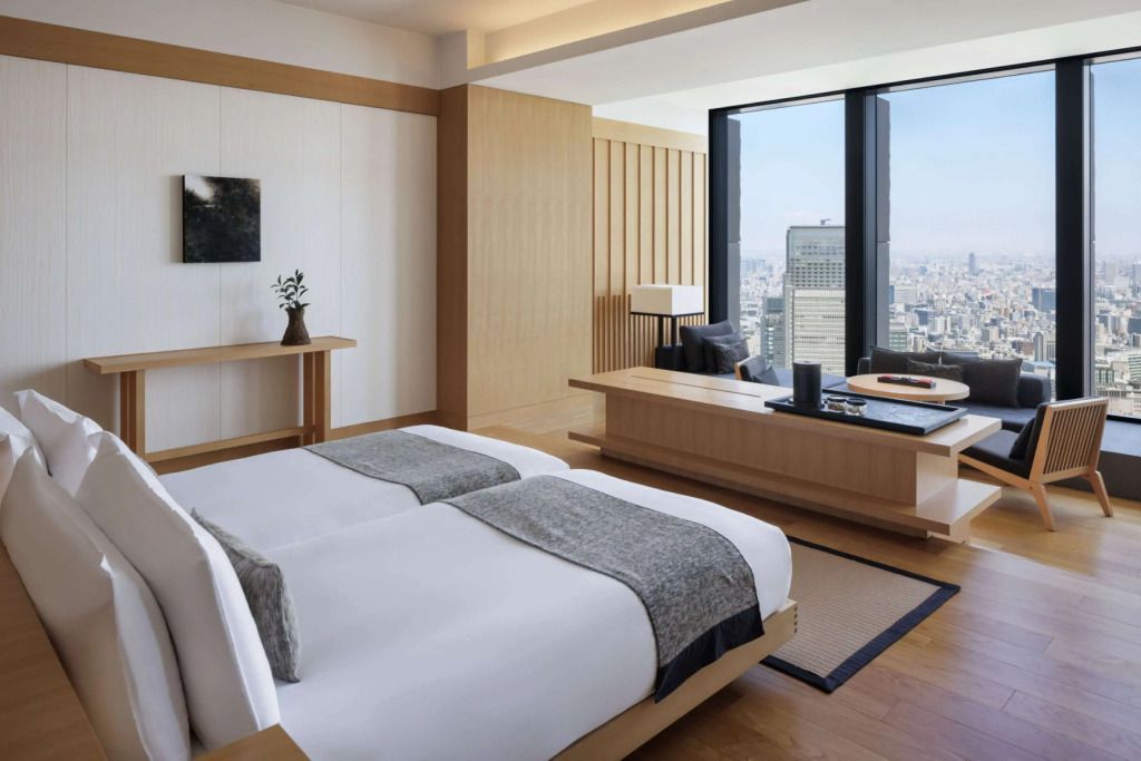 Moderner Raum mit Doppelbett und Aussicht auf die Stadt durch große Fenster