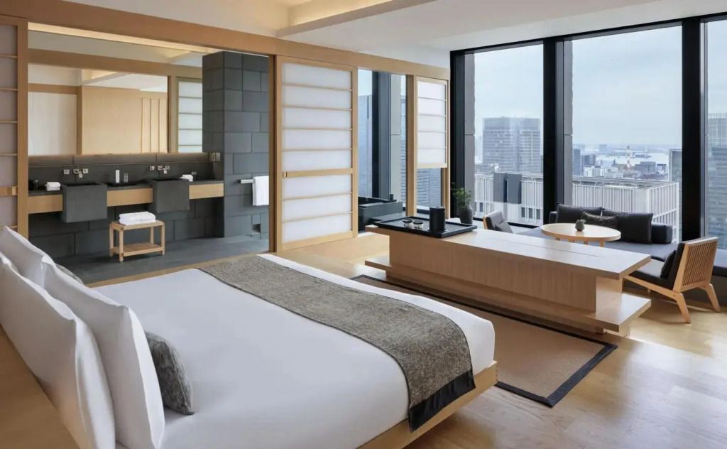 Helles Schlafzimmer mit Doppelbett und Blick auf die Stadt in der Panorama Suite