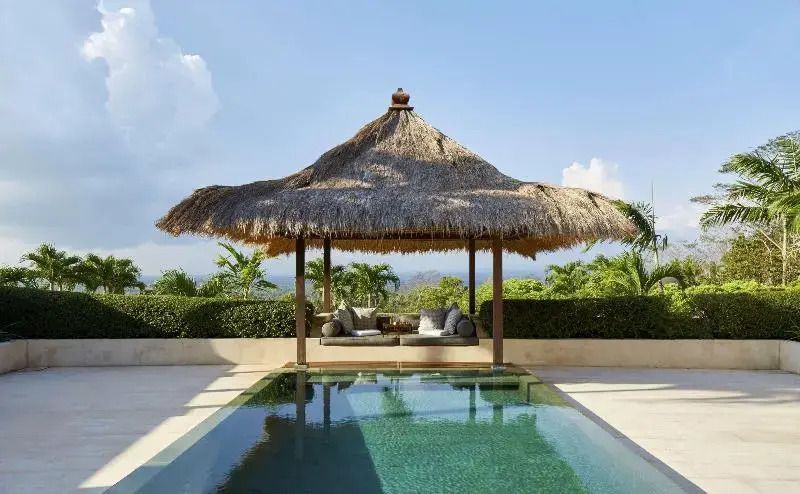 Moderner Pool mit traditionellem Strohpavillon und Fernblick auf die Landschaft