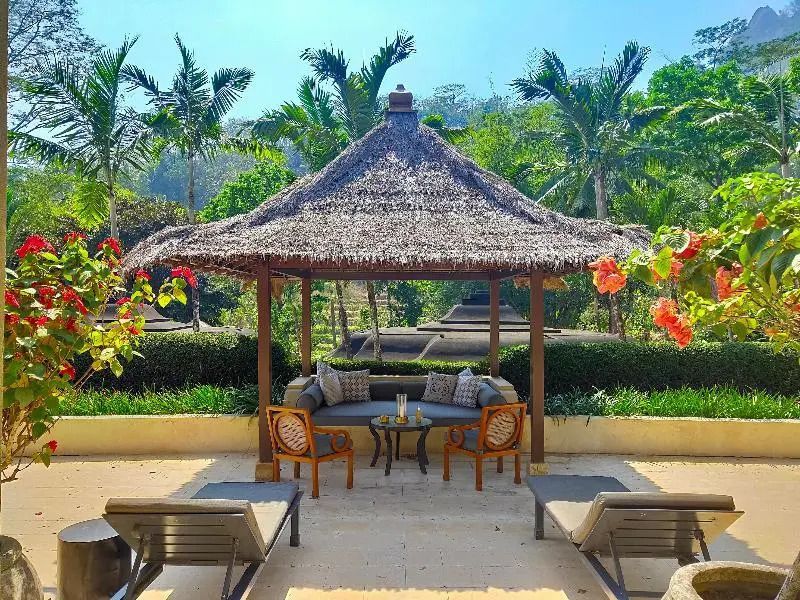 Gemütliche Lounge mit Strohdach und Sitzmöbeln im tropischen Garten.