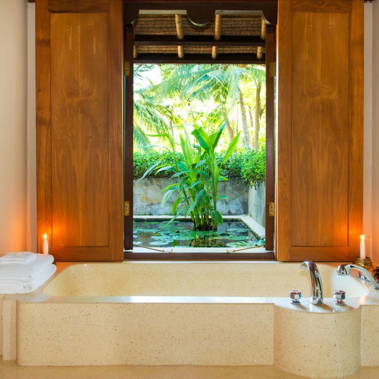 Private Badewanne mit Blick auf üppige Pflanzen durch ein großes Fenster