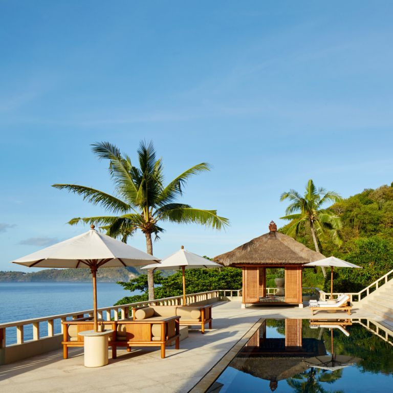 Infinity-Pool mit Sonnenschirmen und Meerblick in tropischer Umgebung