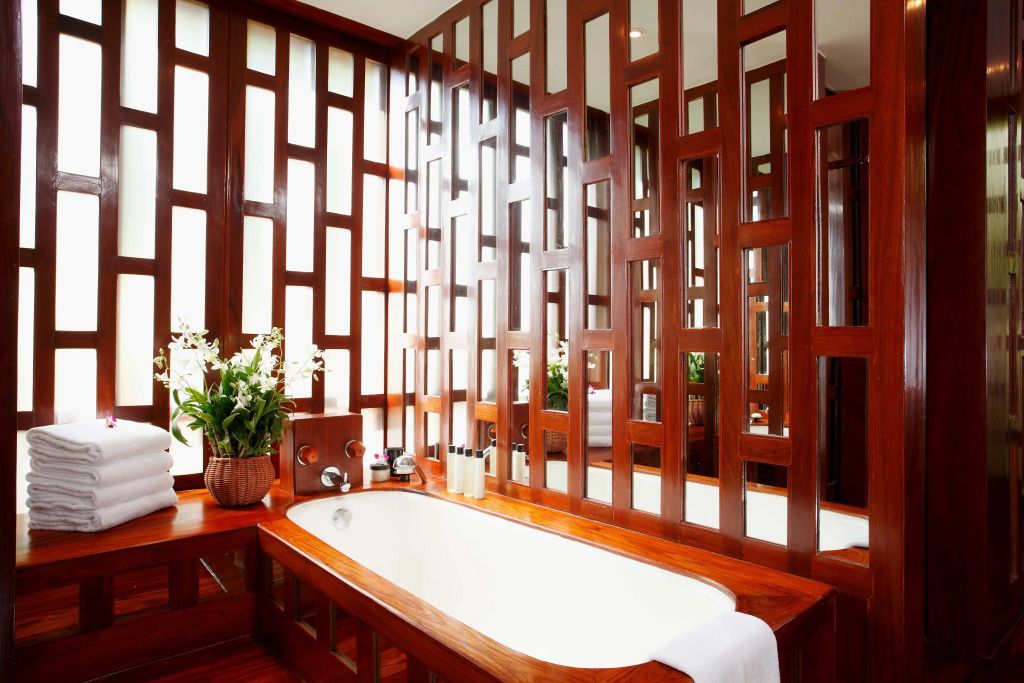 Badezimmer mit großer Badewanne und dekorativen Holzelementen in der Amanpuri Villa