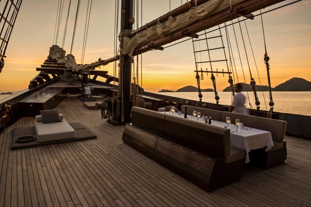 Deck eines Segelschiffs bei Sonnenuntergang mit elegant gedecktem Tisch