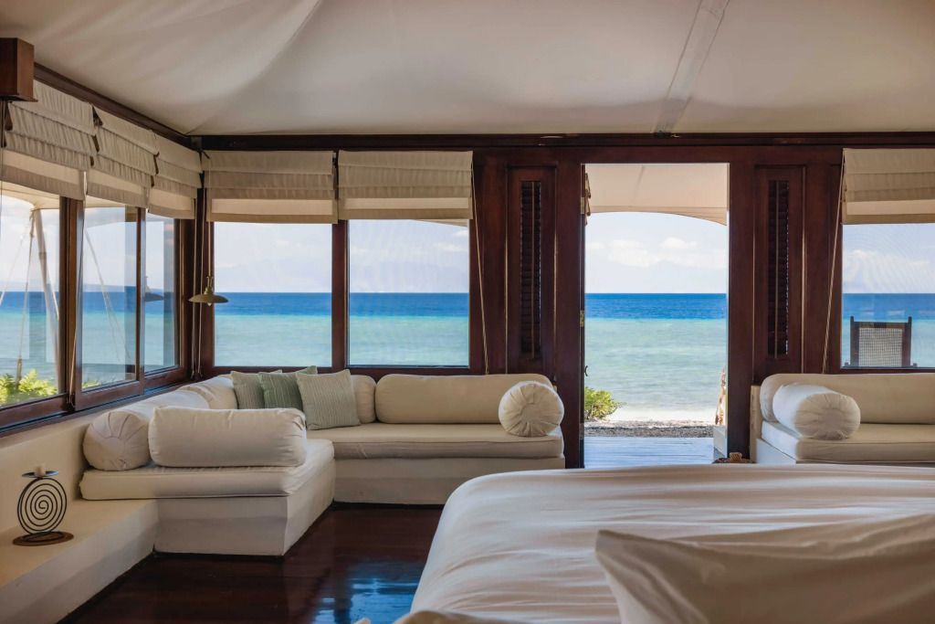 Zimmer mit Blick auf das Meer durch große Fenster. Weiße Sofas und gemütliche Atmosphäre.