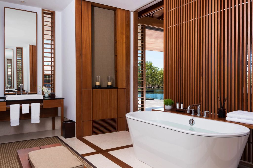 Luxuriöses Badezimmer mit freistehender Badewanne und Holzverkleidung mit Poolblick